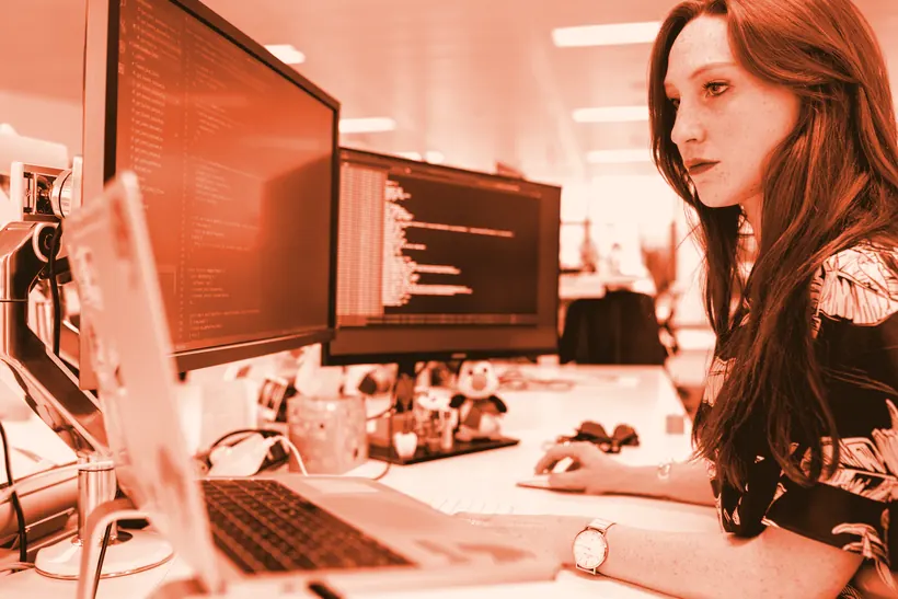 An engineer reading code across two monitors