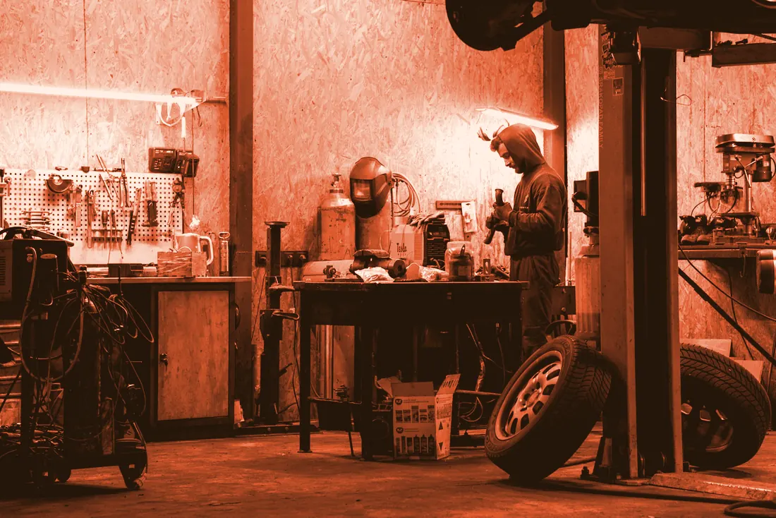 A mechanic at work in a cluttered garage workshop