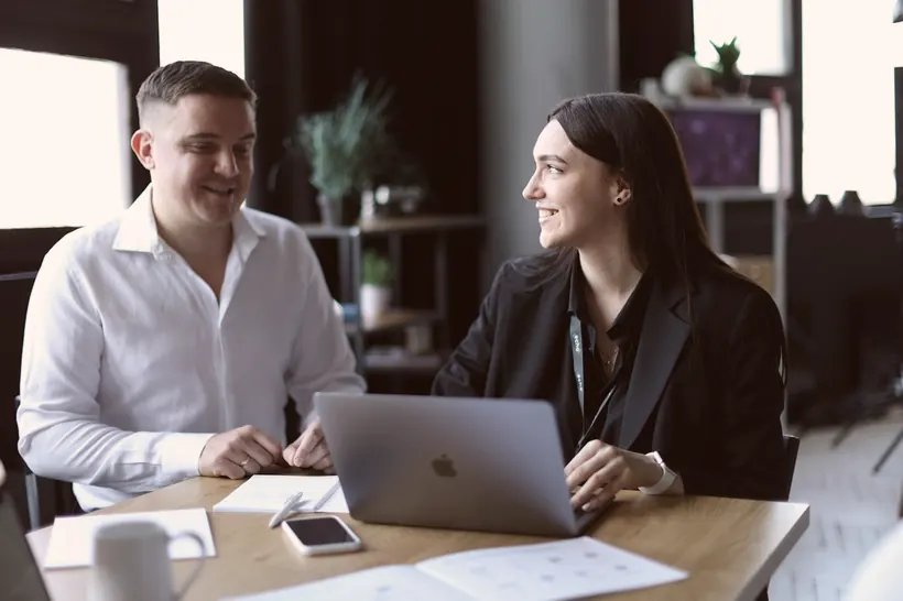 Two people reviewing work together on a laptop